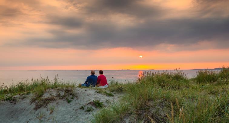 Bildet viser et par som betrakter solnedgangen på en strand i Sola.