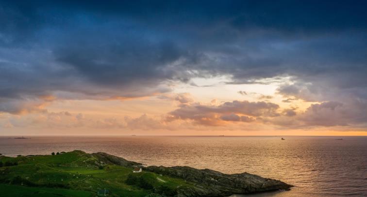 Bildet viser et hus på et ned under en dramatisk himmel på kysten av Sola.