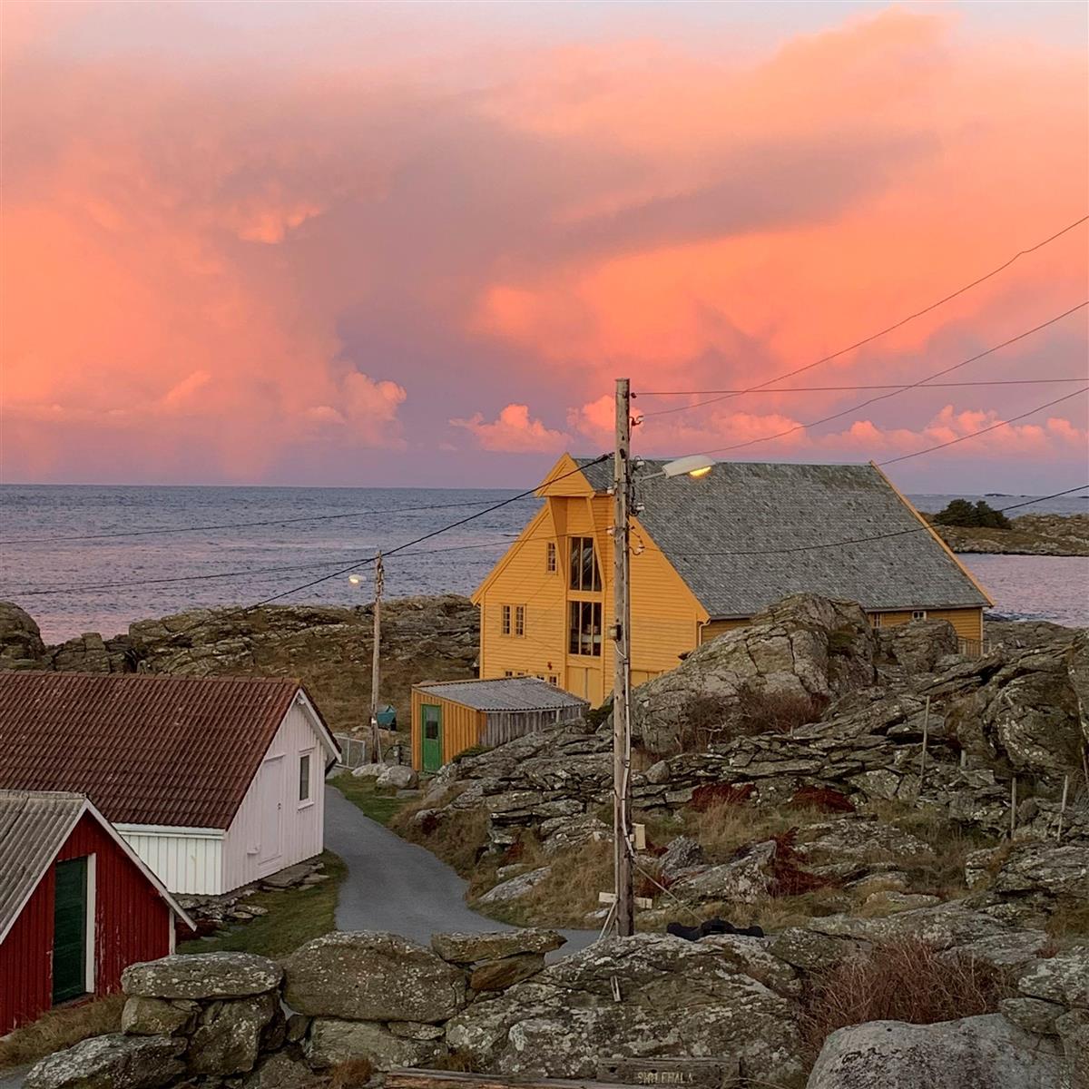 Foto av Sagå, et gult hus i vakkert lys på øya Rott.  - Klikk for stort bilde