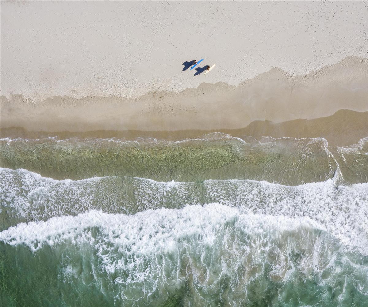 flyfoto av strand med surfere - Klikk for stort bilde